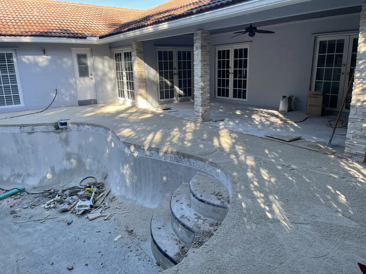 Pool steps and walls chipped down to the shell, old deck removed under the covered patio
