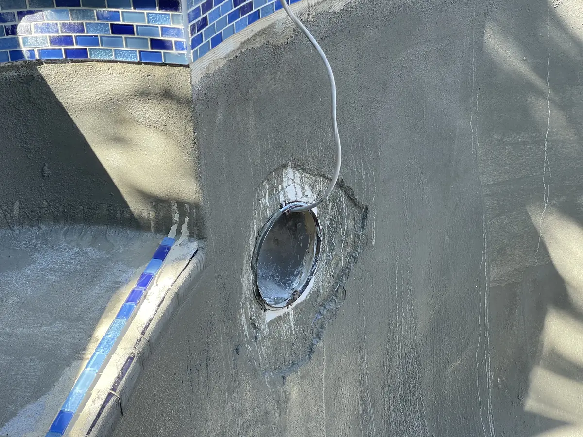 New blue glass waterline tile and a rebuilt light niche on a prepped pool wall