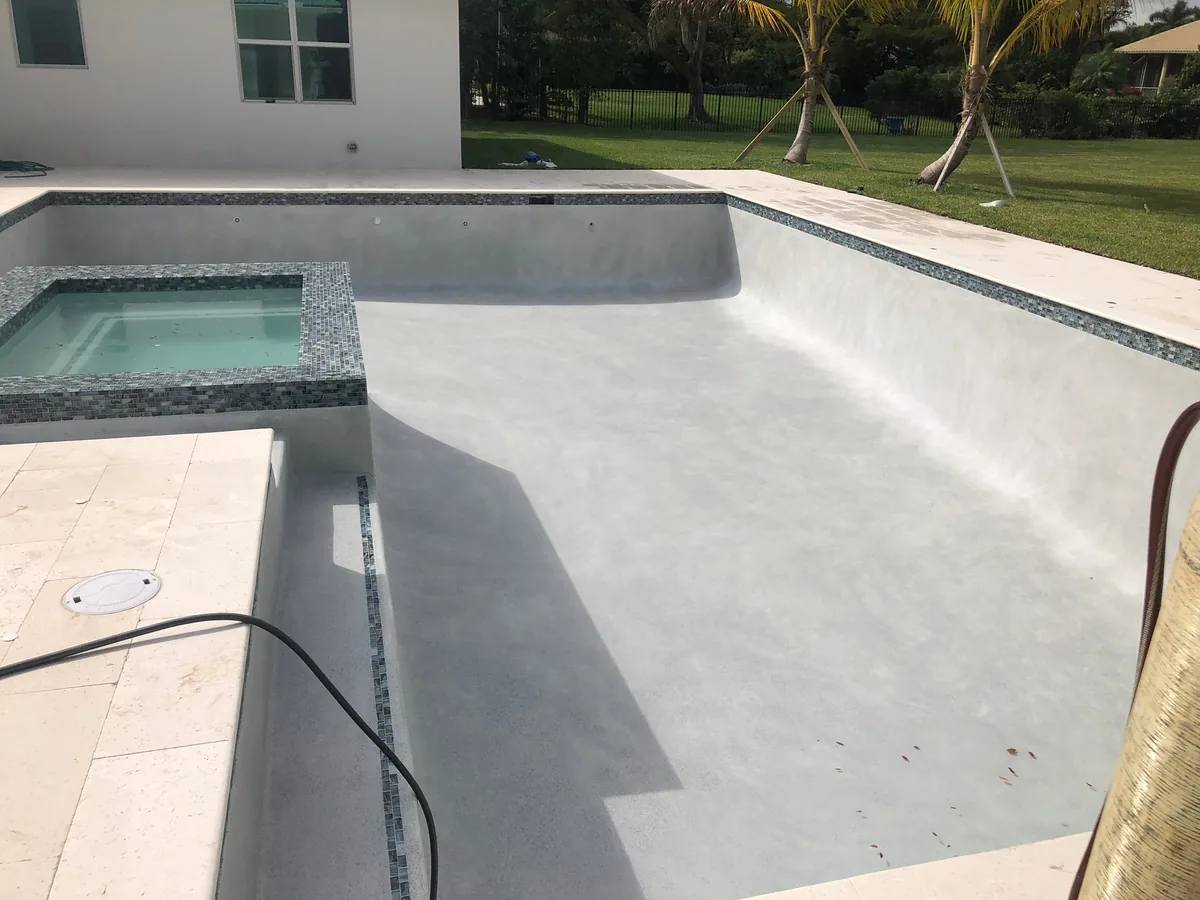 Fresh white interior finish on a rectangular pool with a raised spa and new stone coping
