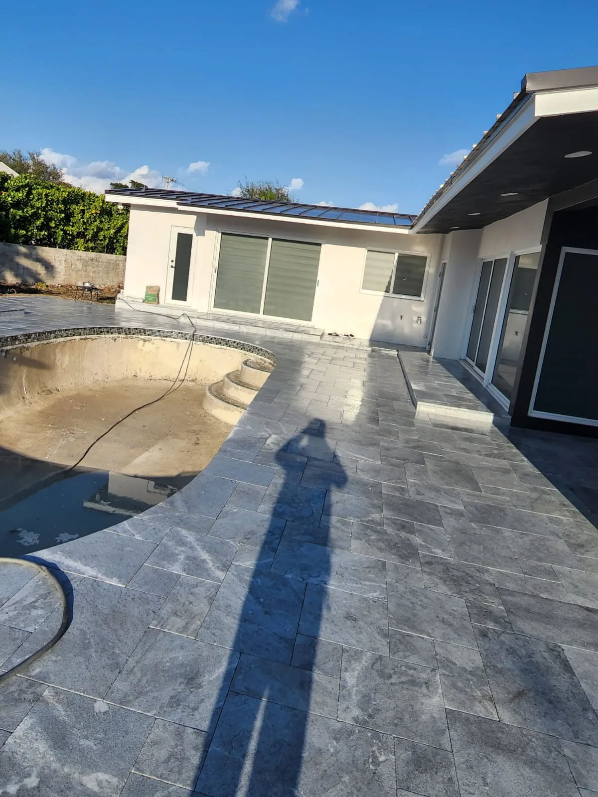 New silver travertine deck around a drained freeform pool waiting for its new finish